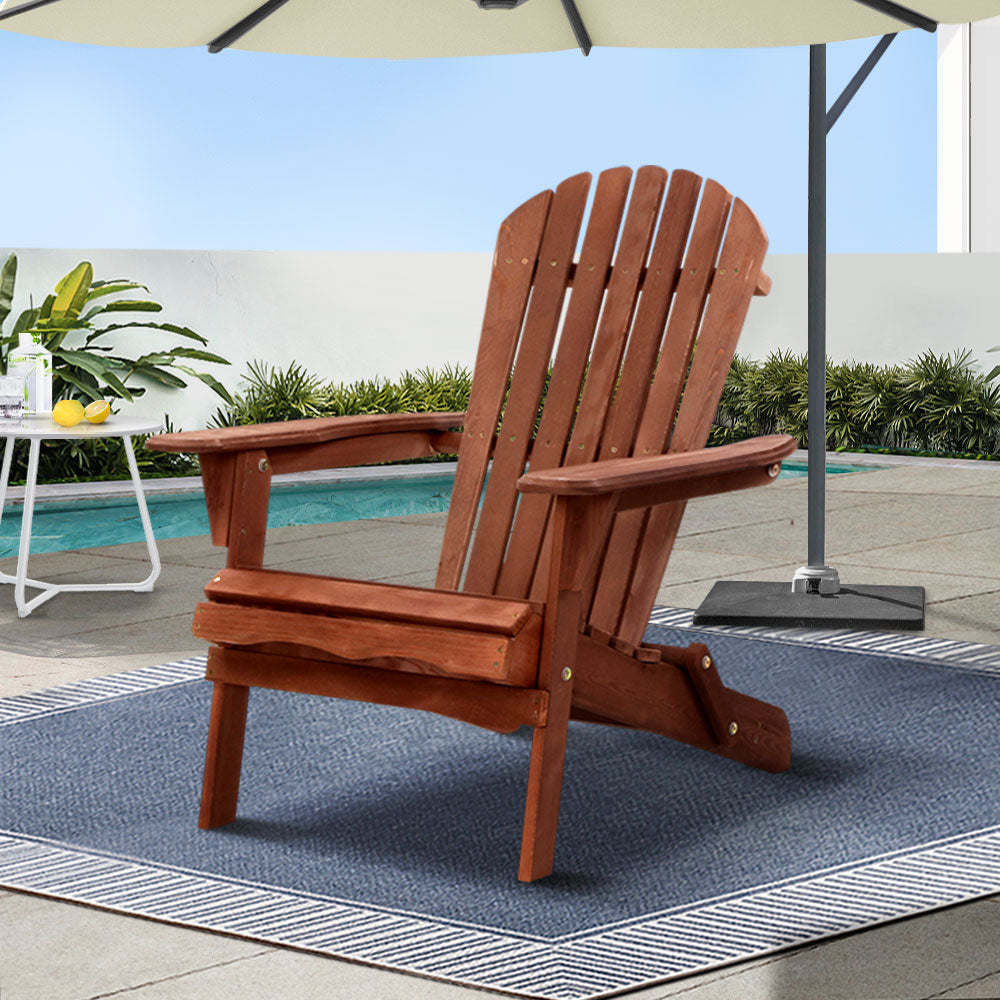 Wooden Adirondack chair on a patio with a pool and umbrella in the background