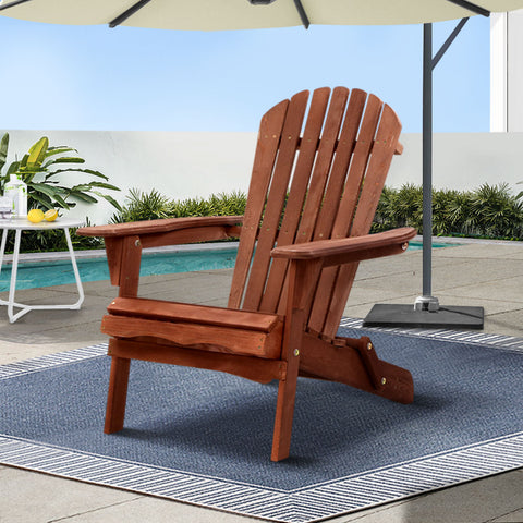 Wooden Adirondack chair on a patio with a pool and umbrella in the background