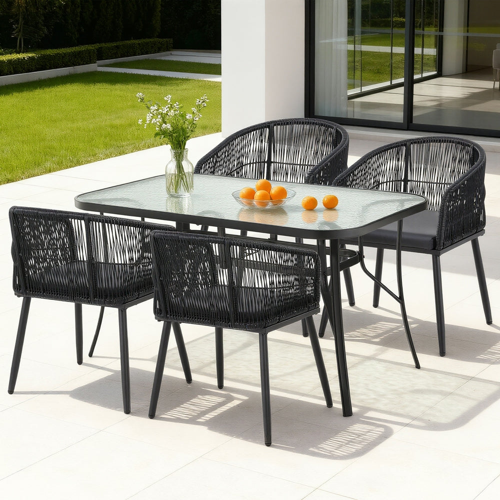 Outdoor dining set with black chairs and a glass table on a patio.