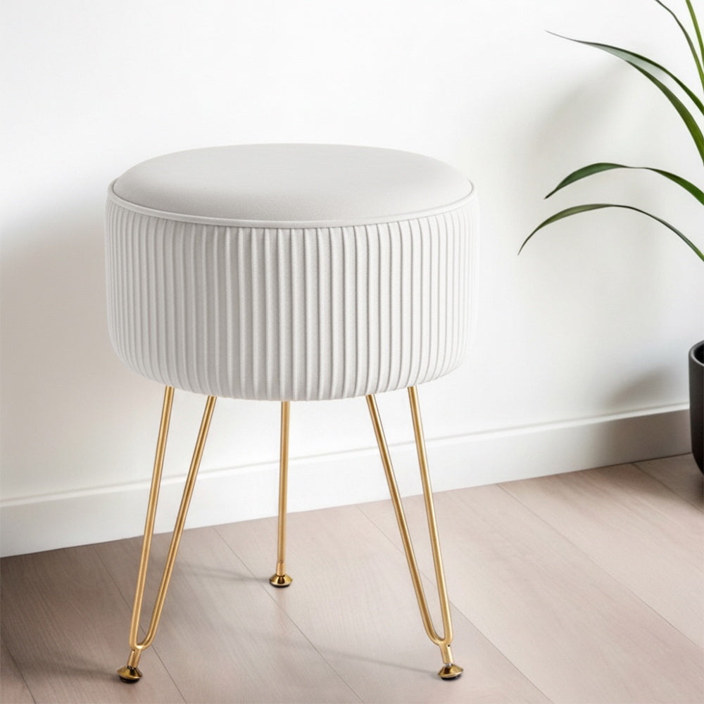 White ottoman with gold legs in a minimalistic room setting