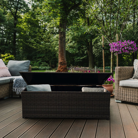Outdoor patio with wicker furniture, fire pit, and greenery
